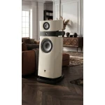Tall white floor-standing speaker with large woofer in a stylish living room setup