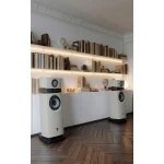 Modern living room with tall white floor speakers, white cabinets, and bookshelves along the wall with soft lighting.