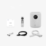 White Wiim wireless speaker with a black circular display, shown with a remote, quick guide, and USB, auxiliary, and power cables nearby