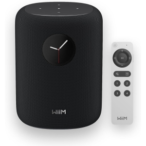 Black WIIM smart speaker with a mesh grille and a round clock on the front, shown with its white remote control beside it.