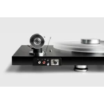 Close-up of a sleek black turntable with a silver platter on the right and a circular metal tonearm assembly on the left, alongside audio connectors on the front panel.