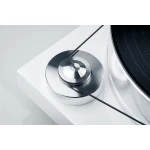 Close-up of a white turntable with a chrome tonearm and a black vinyl record in the foreground.
