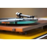 Turntable playing a vinyl record with a green-lit edge and a close-up tonearm ready to play the record