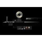 Close-up of a turntable's tonearm and counterweight with RCA outputs (red/white) and ground terminal on a black background; a sleek audio setup is shown from the side.