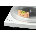 Close-up of a Pro-Ject turntable with a wooden level block resting on the platter, showing speed settings 33 and 45/78 on the white body.
