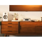 Mid-century wooden sideboard with a white speaker, decorative vase, books, and a silver Marantz stereo on top, TV above.