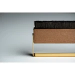 Close-up of a wide, flat brush with black bristles resting on a gold metal holder or stand.