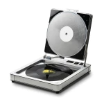 Open-lid portable turntable playing a black vinyl record on a silver chassis.
