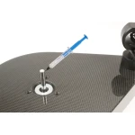 Syringe with blue plunger hovering over a metal shaft on a carbon-fiber lab table.