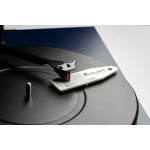 Turntable close-up showing the tonearm and stylus resting on a vinyl record, with a white Pro-Ject calibration tag nearby.