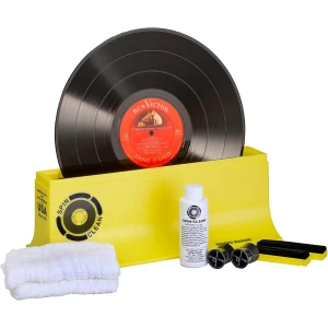 Vinyl record cleaning kit with a yellow box, black record, cleaning fluid, microfiber cloths, and brushes laid out nearby