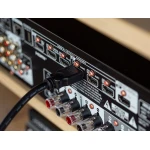 Back panel of an audio/video receiver with HDMI and RCA connectors and cables plugged in, on a black metal plate with labeled ports.